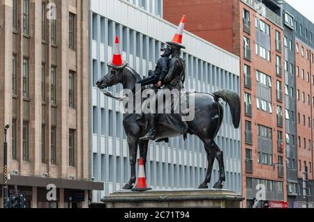 Glasgow, Schottland, Großbritannien. Juli 2020. Ein junger Mann mit Gesichtsmaske klettert die Duke of Wellington Statue hinauf, um drei Verkehrskegel auf den Duke und sein Pferd Kopenhagen zu legen. Kredit: Skully/Alamy Live Nachrichten Stockfoto