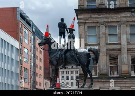 Glasgow, Schottland, Großbritannien. Juli 2020. Ein junger Mann mit Gesichtsmaske klettert die Duke of Wellington Statue hinauf, um drei Verkehrskegel auf den Duke und sein Pferd Kopenhagen zu legen. Kredit: Skully/Alamy Live Nachrichten Stockfoto