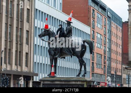 Glasgow, Schottland, Großbritannien. Juli 2020. Ein junger Mann mit Gesichtsmaske klettert die Duke of Wellington Statue hinauf, um drei Verkehrskegel auf den Duke und sein Pferd Kopenhagen zu legen. Kredit: Skully/Alamy Live Nachrichten Stockfoto