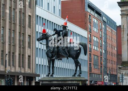 Glasgow, Schottland, Großbritannien. Juli 2020. Ein junger Mann mit Gesichtsmaske klettert die Duke of Wellington Statue hinauf, um drei Verkehrskegel auf den Duke und sein Pferd Kopenhagen zu legen. Kredit: Skully/Alamy Live Nachrichten Stockfoto