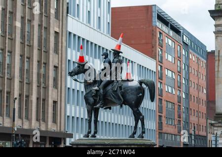 Glasgow, Schottland, Großbritannien. Juli 2020. Ein junger Mann mit Gesichtsmaske klettert die Duke of Wellington Statue hinauf, um drei Verkehrskegel auf den Duke und sein Pferd Kopenhagen zu legen. Kredit: Skully/Alamy Live Nachrichten Stockfoto