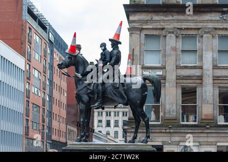 Glasgow, Schottland, Großbritannien. Juli 2020. Ein junger Mann mit Gesichtsmaske klettert die Duke of Wellington Statue hinauf, um drei Verkehrskegel auf den Duke und sein Pferd Kopenhagen zu legen. Kredit: Skully/Alamy Live Nachrichten Stockfoto