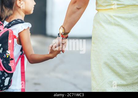 Mutter hält die Hand ihres Kindes und begleitet ihr Kind zur Schule, zurück zur Schule, zum Wissenstag Stockfoto