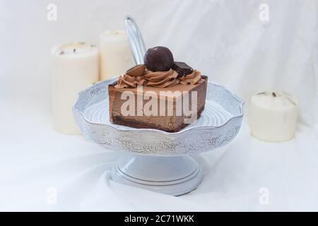 Stück Schokoladenkäsekuchen mit Schlagsahne und Schokoladenkugel auf weißem Hintergrund. Stockfoto