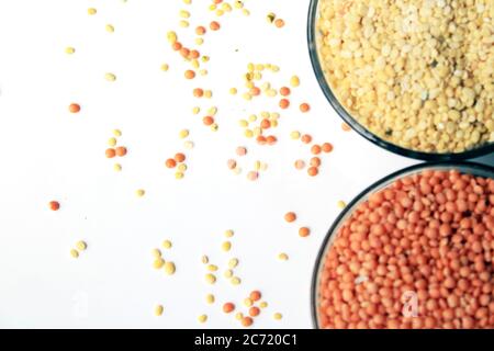 Haufen ungekochte rote Linsen und Taubenerde. Mungbohnen und rote Linsen in zwei Schüsseln isoliert auf weißem Hintergrund. Stockfoto