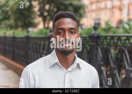 Junge schwarz afrikanischen Mann in der Stadt Gesicht Porträt mit kabellosen Ohrstöpseln Stockfoto