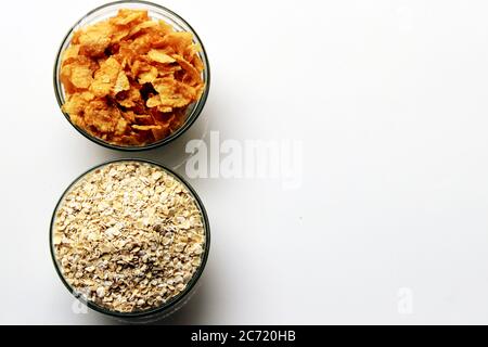 Schüssel voll mit Hafer und Cornflakes. Haferbrei Hafer in Müslischale und Cornflakes auf weißem Hintergrund. Gesunde Ernährung Konzept-Haferflocken und Cornflakes Stockfoto