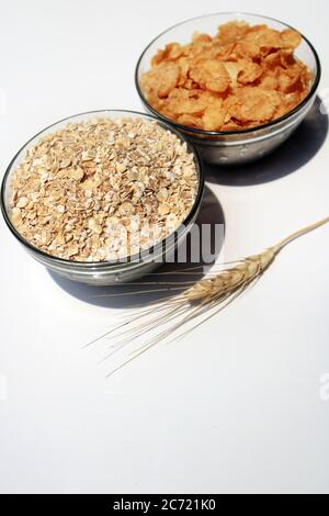 Schüssel voll mit Hafer und Cornflakes. Haferbrei Hafer in Müslischale und Cornflakes auf weißem Hintergrund. Gesunde Ernährung Konzept-Haferflocken und Cornflakes Stockfoto