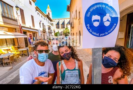 Junge Spanier bedauern und akzeptieren die kommende Generalmaskenpflicht in Spanien. Im Ferienort Santayi gibt es ein Schild, das darauf hinweist, dass Masken CO sind Stockfoto
