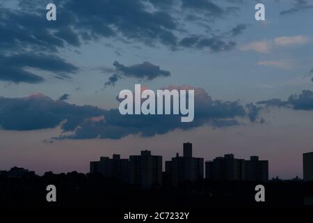 Ein blauer, wolkiger Himmel in der Abenddämmerung mit warmen orange und violetten Untertönen über der Bronx Skyline Stockfoto
