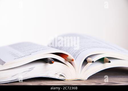 Buch mit bunten Lesezeichen mit Bleistiften auf einem Holztisch mit Platz für Text Stockfoto