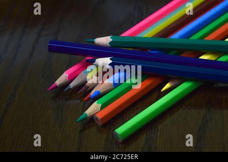 Stapel von verschiedenen farbigen Holz Bleistift Buntstifte in der Oberseite von einander auf einem Schreibtisch platziert Stockfoto