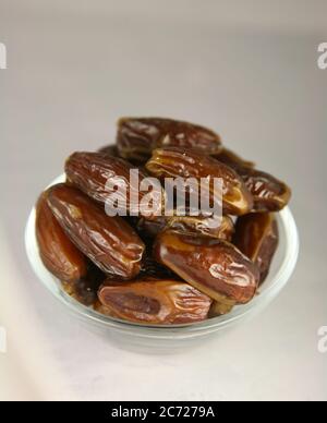 Saftige reife Datteln in einer Glasschale auf einem grauen Tisch Stockfoto