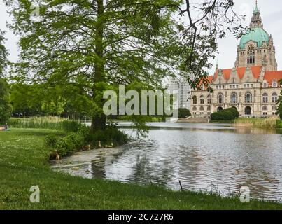 Hannover, 23. Mai 2020: Teich mit einem großen Baum am Ufer hinter dem neuen Rathaus im Maschseepark Stockfoto