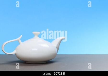 Vintage weiße Porzellan Teekanne auf grauem Brett und blauem Hintergrund. Platz für Text Stockfoto