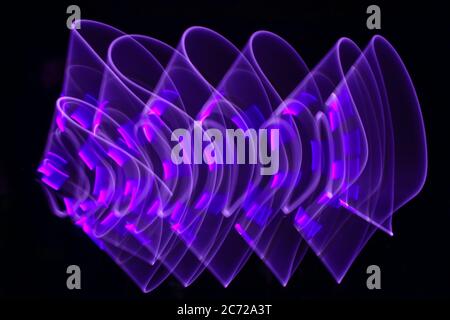Geschwungene abstrakte Form mit einem hellen Säbel violett. Lightenpainting Session bei Nacht. LED-Lichteffekt. Stockfoto