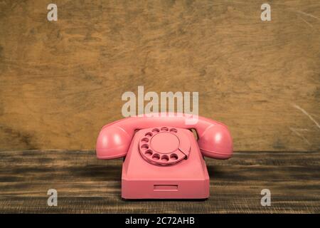 Vintage alten rosa Telefon auf Holztisch mit farbigen Wand Hintergrund Stockfoto