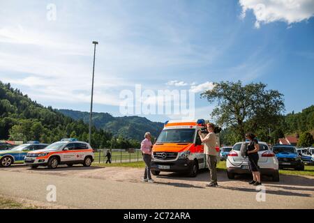 Oppenau, Deutschland. Juli 2020. Ein Medienvertreter und sein Kamerateam berichten über den Stand der Dinge in der Nähe des Hauses der Athleten, das als Treffpunkt für die Polizei dient. Am Montag setzte die Polizei ihre Suche nach einem 31-Jährigen fort, der vier Polizisten in Oppenau im Schwarzwald bedroht und ihnen ihre Dienstwaffen weggenommen hatte. Der Mann, der keinen festen Wohnsitz hat, war nach dem Verbrechen am Sonntagmorgen in den Wald geflohen. Quelle: Philipp von Ditfurth/dpa/Alamy Live News Stockfoto