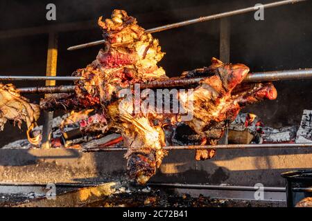 Ein Schwein gegrilltes traditionelles Holz und Feuer. Schwein gegrillt traditionelle Kohle und Feuer. Das kleine Schwein wird auf einem offenen Feuer ganz geröstet. Schwein auf dem Spieß. Stockfoto