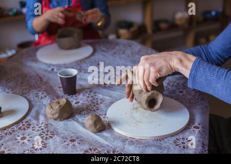 Töpferklasse und Werkstatt: Menschen machen Tonbecher in Töpferei. Handarbeit, Kunst und Studienkonzept Stockfoto