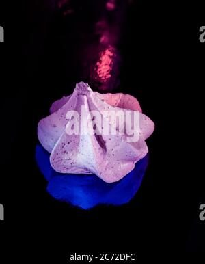 Süßes rosa Baiser auf dunkelblauem Hintergrund. Party Art Konzept. Nahaufnahme. Stockfoto