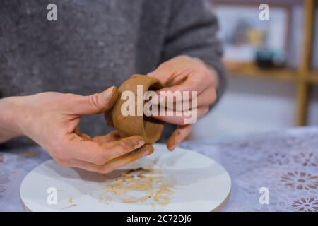 Professionelle männliche Töpfer Herstellung Ton Tee Tasse in Töpferei, Studio. Nahaufnahme. Handgefertigtes, Kunst- und Handwerkskonzept Stockfoto