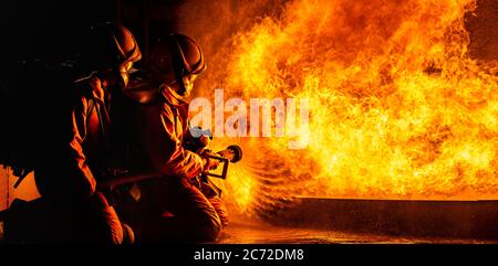 Panorama-Feuerwehrleute mit Twirl Wasser Nebel Feuerlöscher zur Bekämpfung mit der Feuerflamme aus Öl, um das Feuer nicht zu verbreiten zu kontrollieren. Fir Stockfoto