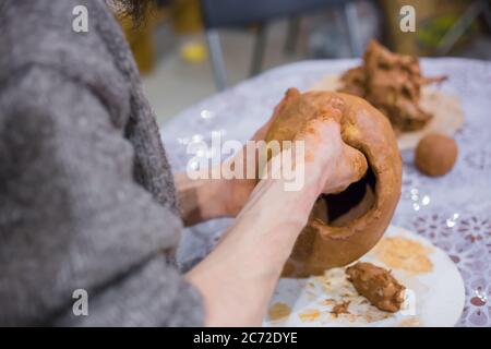 Professionelle männliche Töpfer Hände machen Keramik Krug auf dem Tisch in Töpferei, Studio - Nahaufnahme. Handgefertigtes, Kunst- und Handwerkskonzept Stockfoto