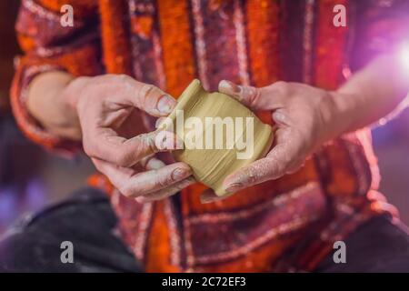 Nahaufnahme Vorderansicht - professionelle männliche Töpfer sitzen und Untersuchung Steingut Tasse in Töpferei, Studio. Handwerk, Kunstwerk und Handarbeit Stockfoto