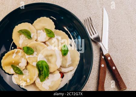 Pilze agnolotti auf blauem Teller. Traditionelles Gericht der italienischen Küche Stockfoto