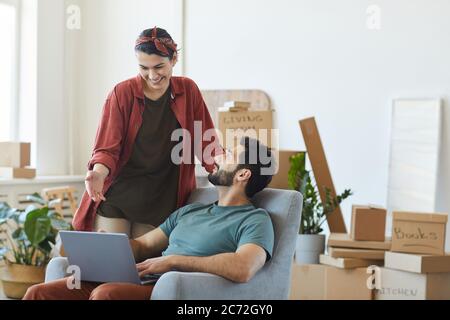 Junge glückliche Paar mit Laptop zusammen, während sie in eine neue Wohnung zu bewegen Stockfoto