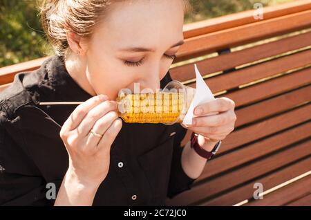 Mädchen essen Mais auf der Cola mit geschlossenen Augen Nahaufnahme. Stockfoto