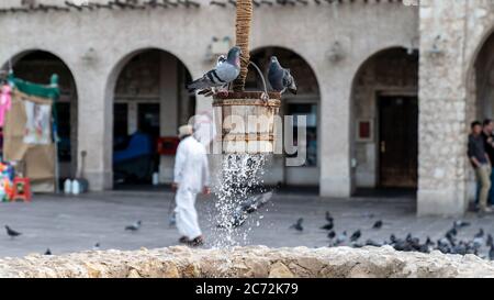 Doha, Katar - Februar 2019: Der alte Brunnen Brunnen Brunnen und Tauben vor Al Fanar Gebäude, in Souq Waqif, Doha, Katar. Stockfoto