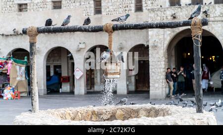 Doha, Katar - Februar 2019: Der alte Brunnen Brunnen Brunnen und Tauben vor Al Fanar Gebäude, in Souq Waqif, Doha, Katar. Stockfoto