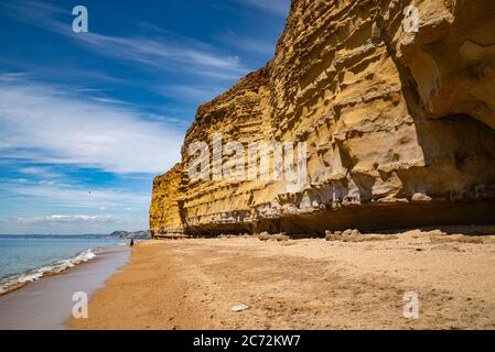 Meeresklippen bei Burton Bradstock, dem Beginn des Chesil-Strandes, an der Jurassic Coast von Dorset, Großbritannien mit blauem Himmel und weißen Wolken Stockfoto