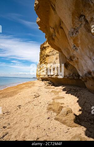 Meeresklippen bei Burton Bradstock, dem Beginn des Chesil-Strandes, an der Jurassic Coast von Dorset, Großbritannien mit blauem Himmel und weißen Wolken Stockfoto