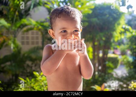 Nettes Kleinkind Baby mit Appetit essen Cookies an einem sonnigen Tag. Stockfoto