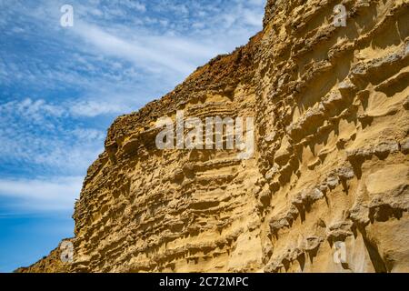 Meeresklippen bei Burton Bradstock, dem Beginn des Chesil-Strandes, an der Jurassic Coast von Dorset, Großbritannien mit blauem Himmel und weißen Wolken Stockfoto