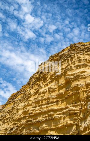 Meeresklippen bei Burton Bradstock, dem Beginn des Chesil-Strandes, an der Jurassic Coast von Dorset, Großbritannien mit blauem Himmel und weißen Wolken Stockfoto