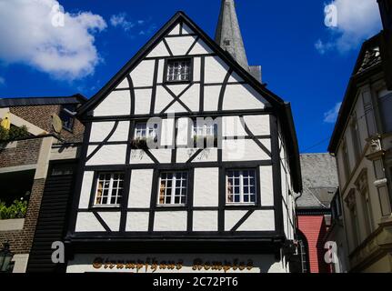 Kempen, Deutschland - 9. Juli. 2020: Blick auf weiße mittelalterliche Fachwerkhaus-Fassade mit katholischem Kirchturm im Sommer mit blauem Himmel Stockfoto