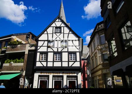 Kempen, Deutschland - 9. Juli. 2020: Blick auf weiße mittelalterliche Fachwerkhaus-Fassade mit katholischem Kirchturm im Sommer mit blauem Himmel Stockfoto