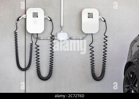 Autoladegerät mit Kabel an Betonwand Stockfoto