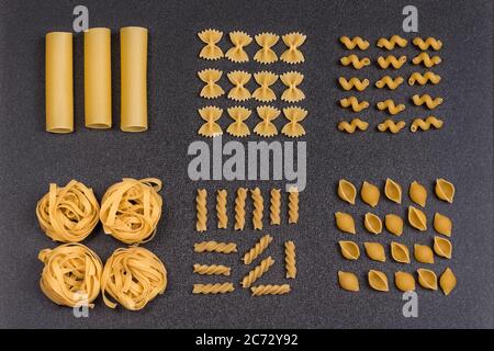 Cannelloni fettuccine conchilioni farfalle Fliege Pasta, Fusilli und cavatappi. Verschiedene Arten von Pasta auf grauem Hintergrund Stockfoto
