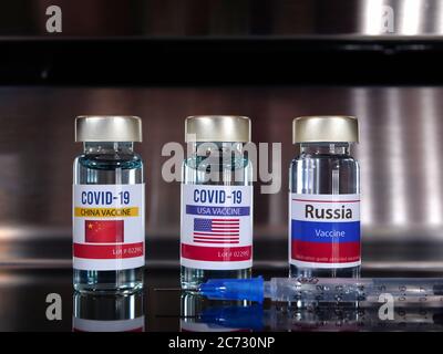 Drei Fläschchen Impfstoff covid-19 Impfstoff mit einem Flaggenschild der USA, China, Russland. Coronavirus Konzept. Stockfoto