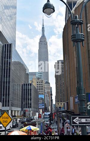 Das Empire State Building, das von einer belebten Straße in New York City aus gesehen wird. Sackgasse und Einbahnstraßen sind sichtbar und eine Straßenlaterne. Stockfoto