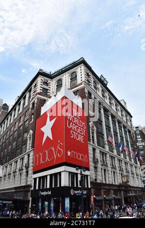 Die große rote Einkaufstasche bei Macy's, dem größten Kaufhaus der Welt in New York City. Amerikanische Flaggen hängen an der Seite des Ladens. Stockfoto