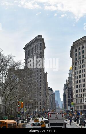 Das Flatiron Building von der Fifth Avenue. Die Straße ist voller Verkehr und hat einen freien Blick am Gebäude vorbei bis zum Finanzviertel. Stockfoto