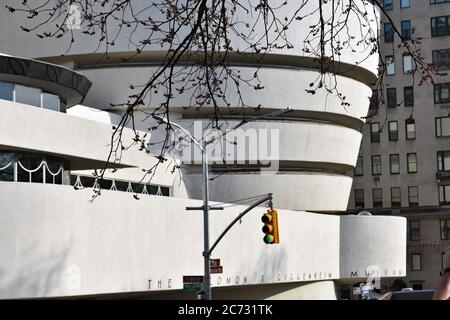 Das Guggenheim Museum auf der Upper East Side in New York City. Ampeln und Bäume stehen im Vordergrund und das weiße moderne Gebäude dahinter. Stockfoto