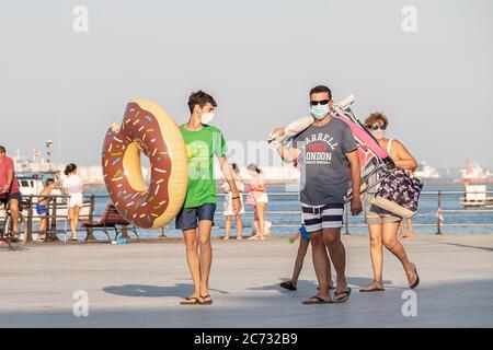 Punta Umbria, Huelva, Spanien - 10. Juli 2020: Eine Familie kommt vom Strand in Punta Umbria Dorf zurück, die Schutzmasken trägt, weil sie covid-19. Neue n Stockfoto