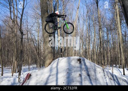 Fahrer springt auf einem Fahrrad im Winter Schmutz springen. Radfahrer machen einen Trick Stockfoto